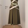 Waldgrünes Wickelkleid mit Kragen und angeschnittenen Ärmeln, knielang, schwingender Rock. Darüber gekreutze Lederbänder, die Lederkorsage über die Hüften formen.