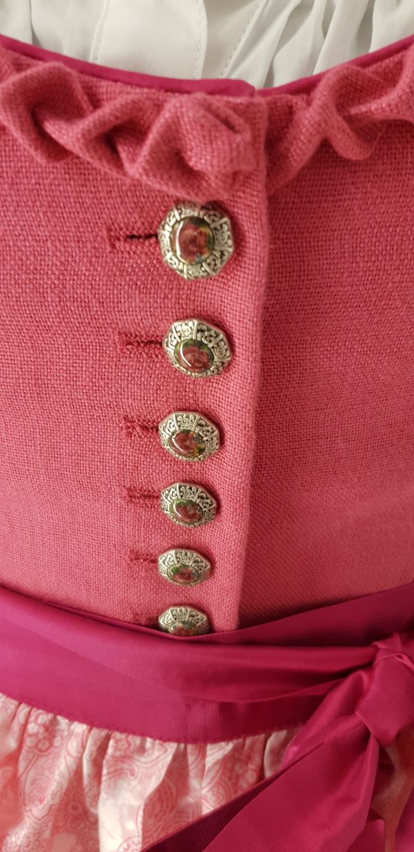 Offizielles "Pink Ribbon" Dirndl von Sportalm, rosa Leinenleib mit Froschgoscherl, edlen Silberknöpfen mit Rosenmotiv, rosa Rock mit Blumenmuster, mit hochgeschlossener weißen Spitzenbluse, Schürze weiß mit rosa Paisleymuster und pinkem Schürzenbank mit Strasssteinen