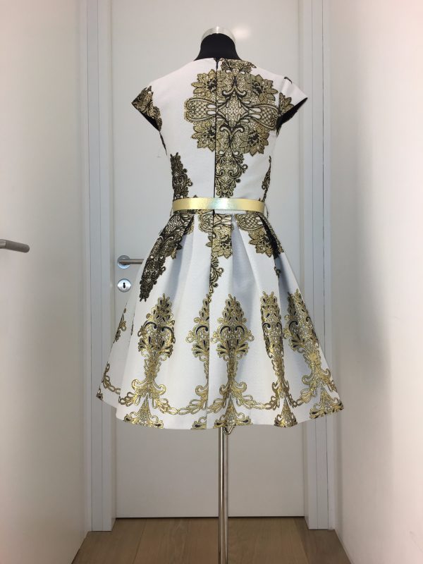 Kurzes Cocktailkleid mit weiß-goldenem großen Ornamentmuster, schmaler Gürtel, V-Ausschnitt und weit schwingendem Rock
