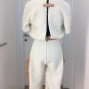 Winterweißer knielanger Jumpsuit mit hellen Naturlederaufschlägen und seitlichen Taschen, Rücken offen mit Spangen gehalten