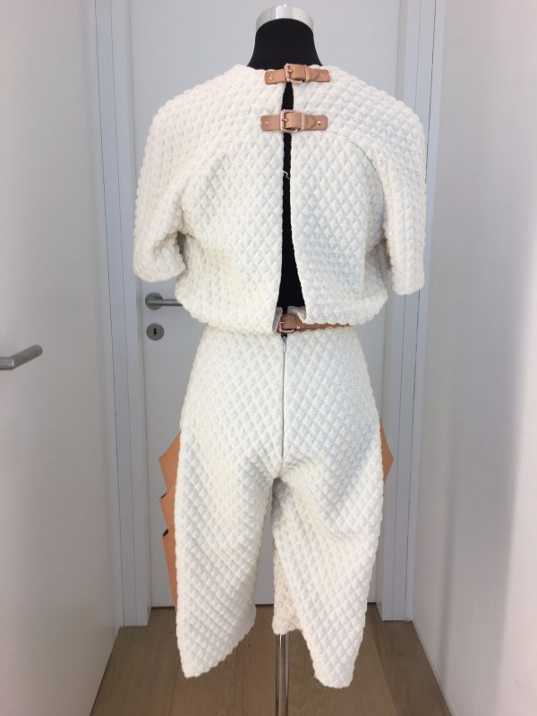 Winterweißer knielanger Jumpsuit mit hellen Naturlederaufschlägen und seitlichen Taschen, Rücken offen mit Spangen gehalten