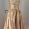 Gold-rose glänzendes Cocktailkleid mit Wickeloptik und doppelten Spitzen am Bustier, weitschwingender Rock, knielang