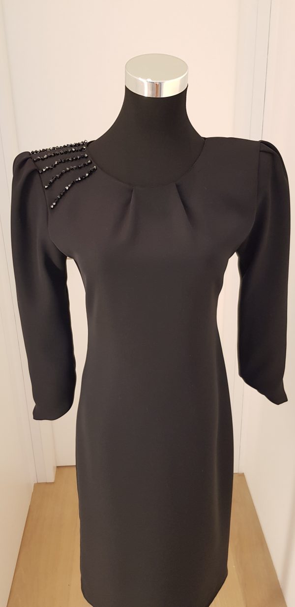 Schlichtes, schwarzes Cocktailkleid mit Strass auf der rechten Schulter, asymmetrischer Ärmelabschluss, knielang, breite Schultern