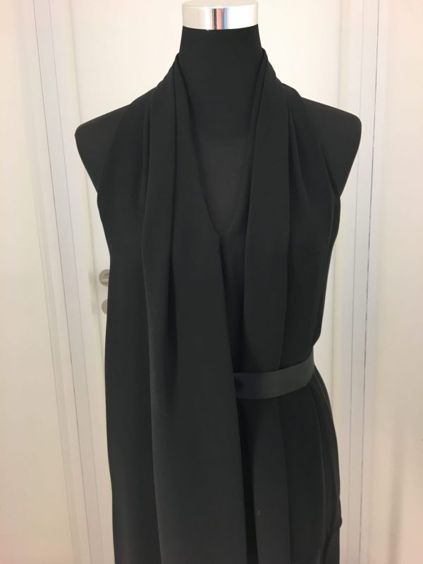 Asymmetrisches schwarzes Gürtelkleid ohne Ärmel, vorne ein langer freischwingender Faltenteil